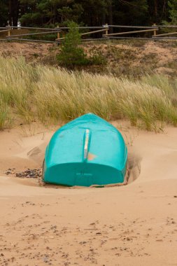 Kumlu deniz kıyısında yeşil bir tekne. Rüzgarlı bir sonbahar günü