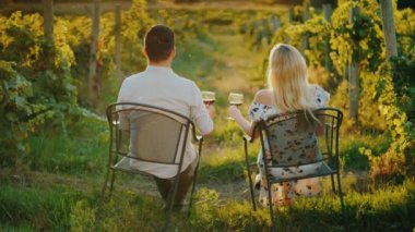 Çok ırklı genç bir çift üzüm bağında dinleniyor, şarap içiyor ve gün batımını seyrediyor. Şarap turu