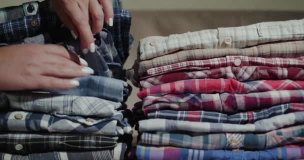 Las manos de las mujeres clasifican a través de una pila de camisas para hombre — Vídeo de stock