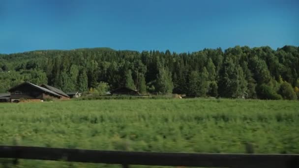 Traditional red wooden houses and picturesque nature - a view from the window of the vehicle — Stock Video