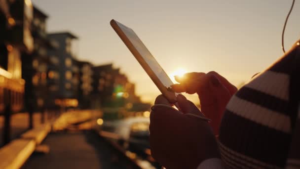 Close-up shot Handen van een vrouw met een smartphone op de achtergrond van een pier met jachten bij zonsondergang — Stockvideo