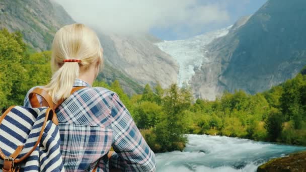 Una donna ammira la vista di un fiume di montagna e di un ghiacciaio in Norvegia — Video Stock