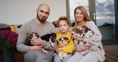 Bir çocuklu ve evcil hayvanı olan bir aile, karlı evin verandasında oturur. Mutlu Bir Aile Portresi