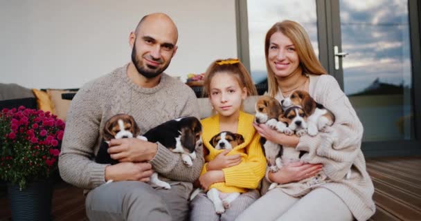 Une famille avec un enfant et un animal de compagnie se trouve sur la véranda de la maison blanche. Portrait d'une famille heureuse — Video