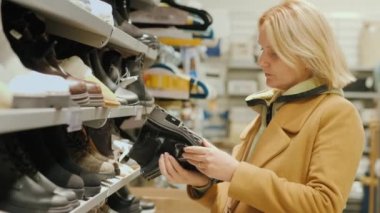 Orta yaşlı bir kadın mağazadan sıcak ayakkabılar seçer.