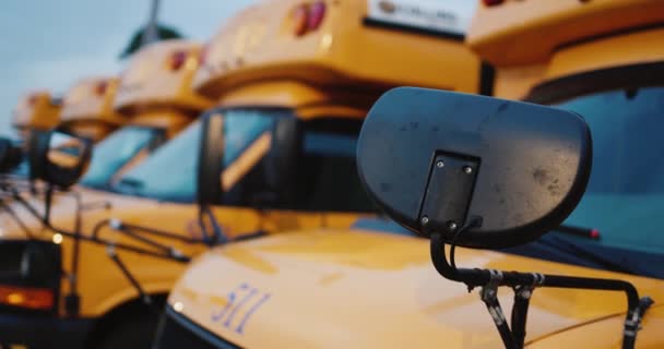 Een aantal schoolbussen voor het vervoer van schoolkinderen. Close-up van auto-onderdelen en achterste rij van andere voertuigen — Stockvideo