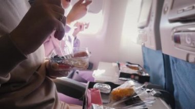 Coronavirus salgını sırasında uçakta yemek. Yolcular koruyucu maskelerle yemek yiyor.