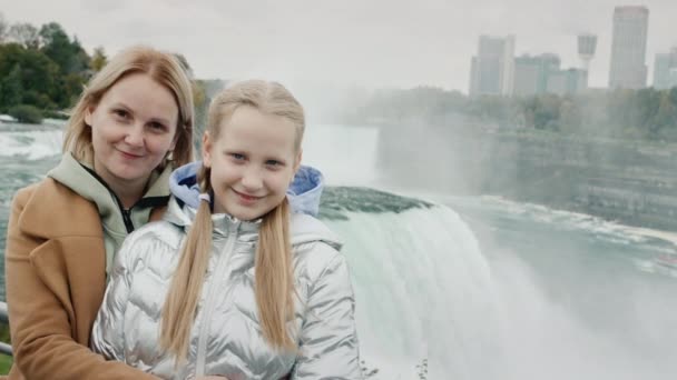 Porträtt av en mor med en dotter på tio år mot bakgrund av den berömda Niagarafallen — Stockvideo