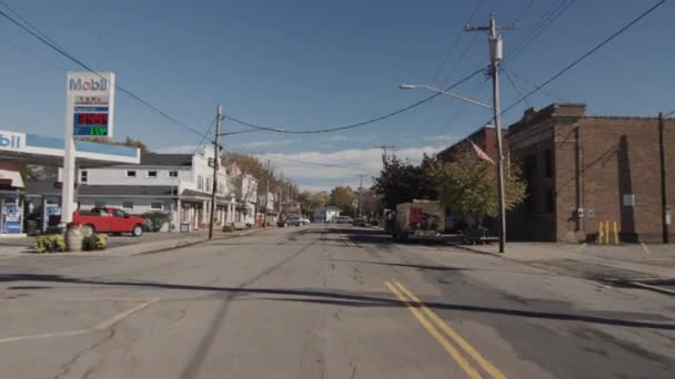 Wilson, NY, USA, październik 2021: Typowa ulica w małym amerykańskim miasteczku, widziana z tylnej szyby przejeżdżającego samochodu. Po bokach znajdują się domy i małe sklepy, typowe amerykańskie znaki drogowe — Wideo stockowe