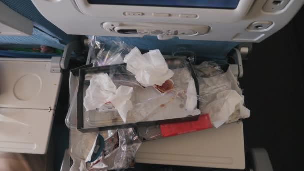 비행기 객실에서 음식을 먹을 수있는 테이블. 플라스틱 과 종이로 된 포장 이 많습니다. 상업 비행의 쓰레기와 낭비 — 비디오