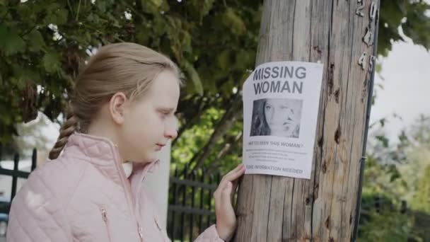 一个悲伤哭泣的孩子站在一个失踪妇女的广告前. — 图库视频影像