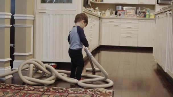 Asiatisches zweijähriges Kleinkind versucht in einem Raum zu staubsaugen — Stockvideo