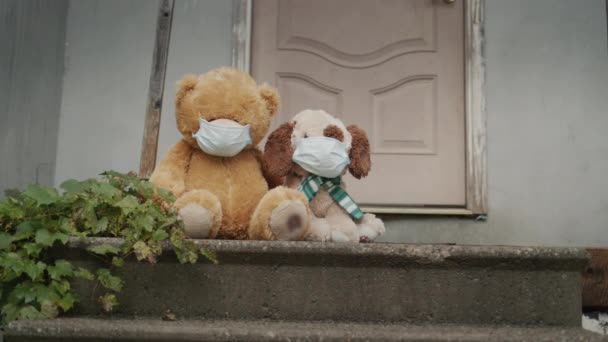 Två leksaker i skyddsmasker sitter på tröskeln till huset. Slut på självisolering och hopp — Stockvideo