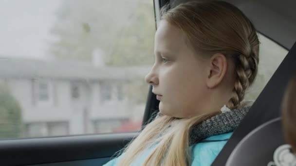 A girl of ten years old rides in the back seat of a car — Stock Video