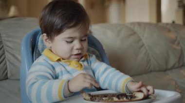 Asyalı bebek pizza yer, bebek beslenme masasına oturur.