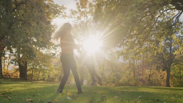 A happy young mother circles her child, has a good time together on a walk. Against the backdrop of sunset — Stock videók