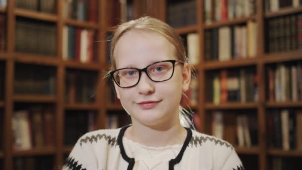 Porträtt av en student på bakgrunden av hyllor med böcker i biblioteket — Stockvideo