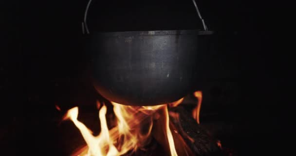 Olla de hierro fundido colgada en una estufa de leña, cocinando en un fuego abierto — Vídeos de Stock
