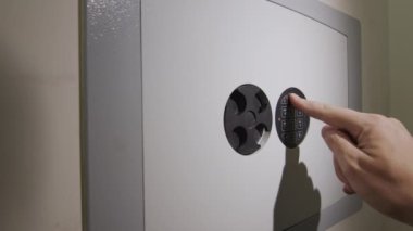 A man puts a wad of money in a safe, where there are already weapons and documents. Criminal Income Concept
