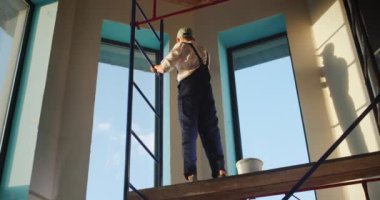 İşçi duvarı asar, iskelenin tepesinde durur..