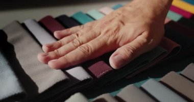 The tailors hand looks at samples of fabric for sewing clothes. Handmade and craft concept