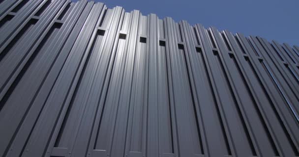 Dolly shot: Grey metal shuttle fence against blue sky. 4k video — Wideo stockowe