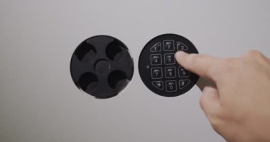 Businessman enters password on electronic lock of safe and opens iron door