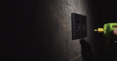 A mans hand inserts an electric fumigator into a socket on the wall