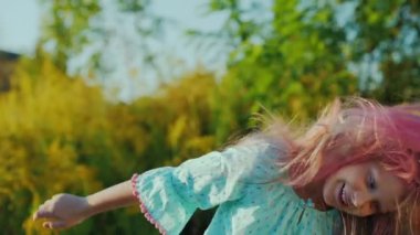 A carefree baby with pink hair shakes his head