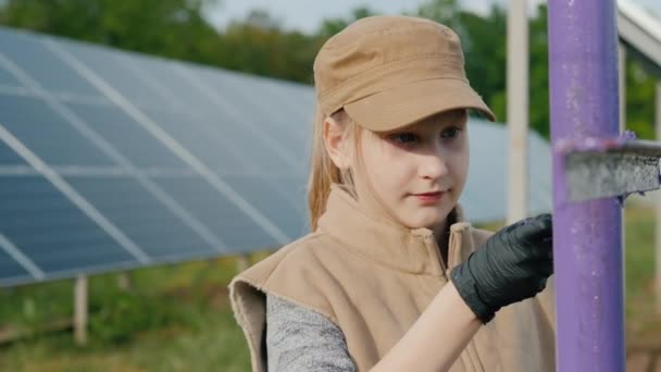 Bir çocuk güneş enerjisi santralinde kutupları boyuyor. — Stok video