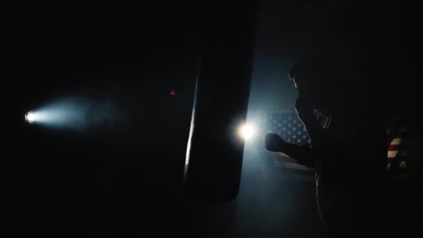 La silhouette d'un combattant qui s'entraîne au gymnase, en arrière-plan du drapeau américain — Video