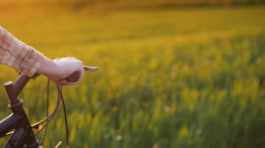 Kadınlar ellerini bisikletin gidonuna koyar, yeşil çayırlarda gezer.