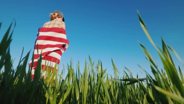 A woman with a U.S. flag stands on a picturesque green meadow — Stock Video