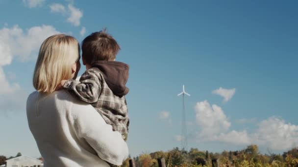 Una madre le muestra a su hijo un generador eólico instalado en su granja. — Vídeo de stock