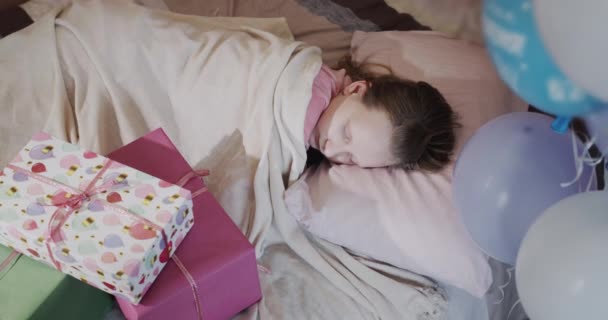 Un bambino dorme nel suo letto, accanto a scatole regalo e palloncini. Vista dall'alto — Video Stock