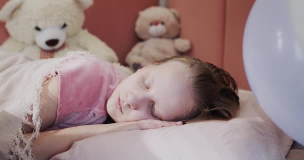 彼女のベッドで寝ている女の子の肖像画,彼女のおもちゃの背景に — ストック動画
