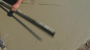 İnşaatçı sıvı betonu düzleştiriyor ve düz bir kör alan oluşturuyor.