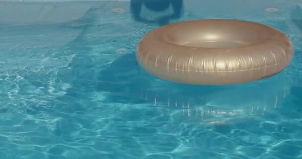 Ένα επιδέξιο παιδί πηδάει στη μέση ενός φουσκωτού κύκλου που κολυμπάει στην πισίνα. — Αρχείο Βίντεο