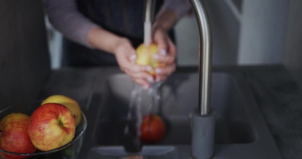 Vue d'en haut : Une femme lave une pomme rouge juteuse sous un robinet. — Video