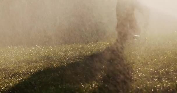 Dos mujeres descalzas corren sobre la hierba verde en chorros de agua. Vídeo en cámara lenta 4k. Concepto de juventud y salud — Vídeos de Stock
