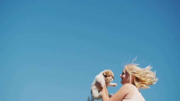 Yavaş çekilen video - bir kadın elinde bir köpek yavrusu tutuyor, gökyüzüne yükseğe zıplıyor. — Stok video