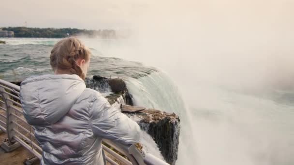 Egy tíz éves gyermek csodálja a híres Niagara vízesést. Utazás az USA-ban — Stock videók