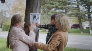 Çocuklu bir kadın kayıp bir yavru köpek ilanı veriyor.