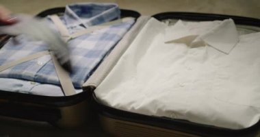 Adam iş seyahati için eşyalarını bir çantaya koyup koruyucu maskeler takıyor..