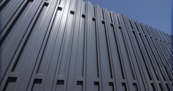 Ein Zaun aus grauen Metallstreifen. Gegen den blauen Himmel — Stockvideo