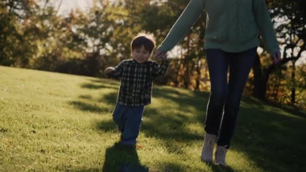 A mother with a cheerful Asian baby walks in the park — Video