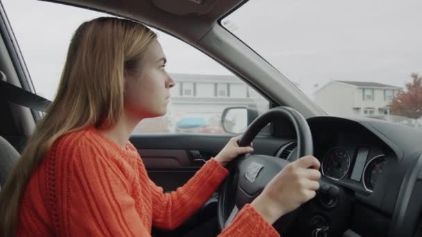 Una joven enfocada conduciendo un auto conduce a través de un suburbio americano. — Vídeo de stock