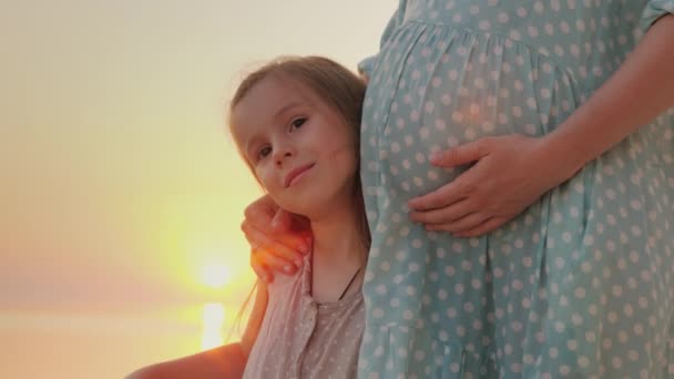 Porträt eines glücklichen kaukasischen Mädchens von sechs Jahren am Bauch ihrer schwangeren Mutter — Stockvideo
