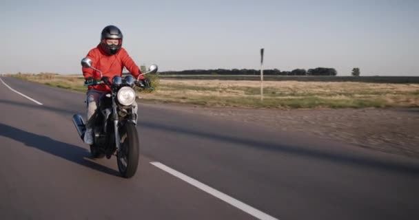 A young man rides a motorbike along corn fields. — стоковое видео