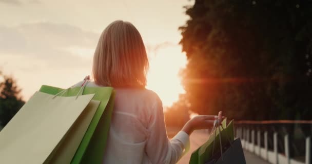 A customer with colorful bags carries purchases — Stock videók